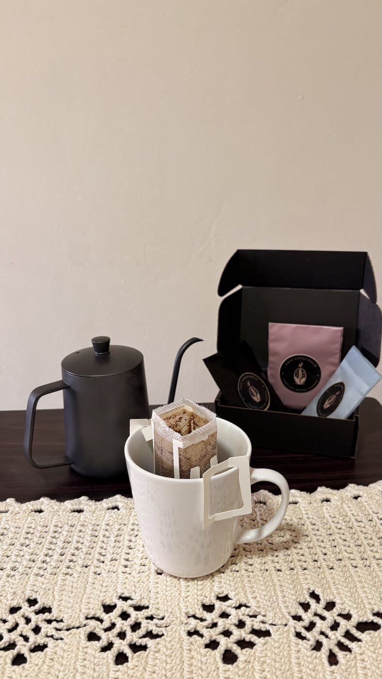 Drip bag montado sobre una taza, junto a un hervidor de cuello de ganso